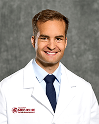 Headshot of medical student Alex Dills in white coat.