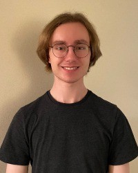 A headshot of Grant Folkert wearing a black tshirt and glasses.