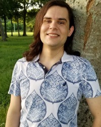 Headshot of Alex Silvagnoli standing outside wearing a blue and white shirt.