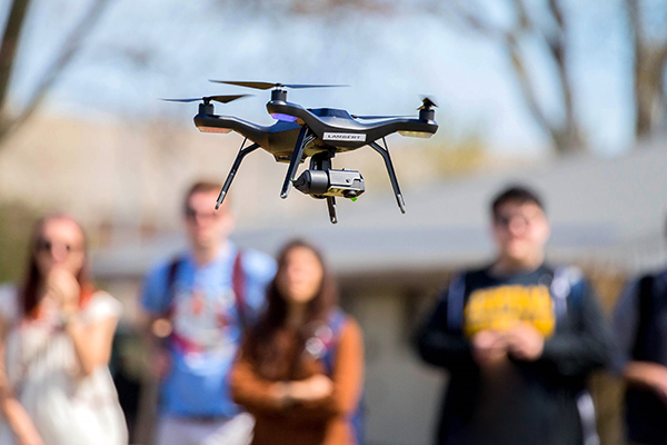 Drone taking flight with a group of students in the background