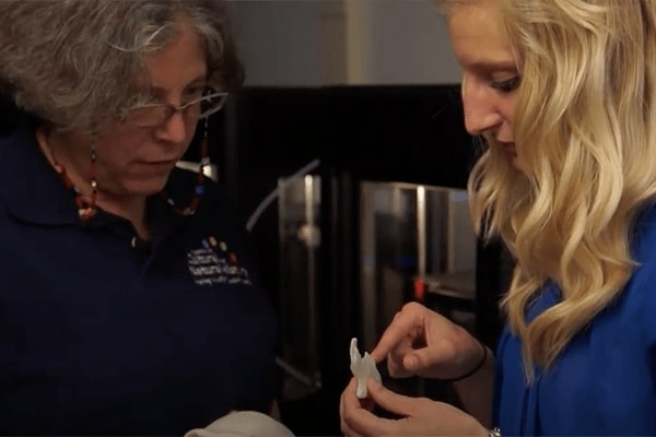 Two women examining a printed figure from the Makerbot 3D printer.