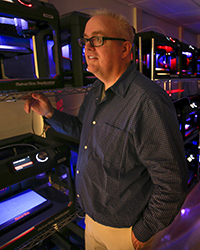 Larry Burditt in the Makerbot lab when it was first opened. You can see the wall of 3D printers behind him.