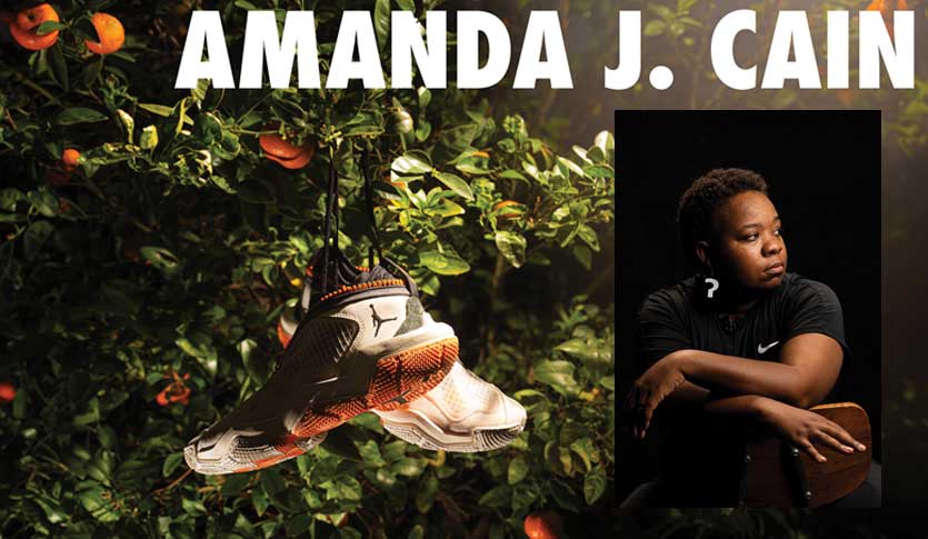 The name Amanda J. Cain is bold across the top of the image. There is an orange tree with a pair of Nike Air Jordans hanging in it. There is also a headshot of Amanda, sitting in a chair, wearing all black with a black background.