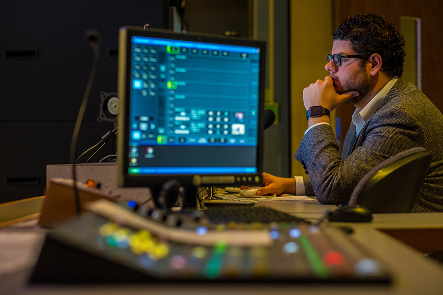 CMU Alum working on computers and state of the art equipment in a media booth