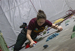 Environmental Recreation student Camille Cashen climbing the rock wall in Finch Fieldhouse