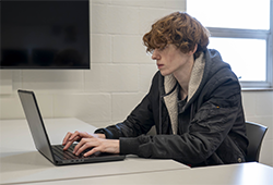 Information Technology student Malachi Swaling-Stickler sitting at his laptop, working on some coding