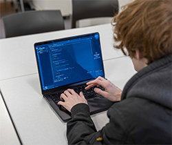 Information Technology student Malachi Swaling-Stickler sitting at his laptop, working on some coding