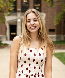 Headshot of Sarah Kelly standing in front of Warriner Hall