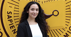 Headshot of Teagan Kazim standing in front of the CMU seal