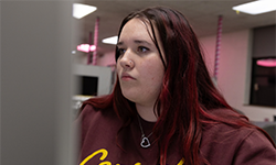 Graphic Design student Zoey Lawrence sitting in front of a computer screen, working intently