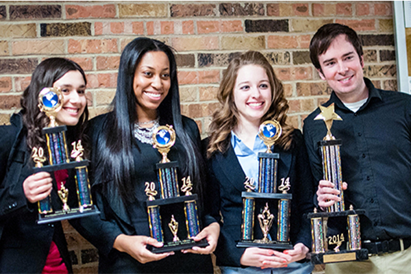 Department of Communication students holding trophies in the College of Art and Media's Moore Hall.
