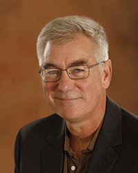 Headshot of Ed Hinck set in front of a gold backdrop.