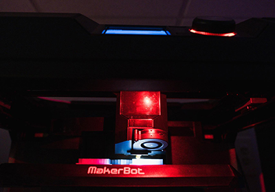 A red light glows on one of the machines in the Makerbot Innovation Center.