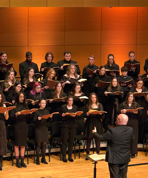 A picture of the CMU Choirs, under the direction of Dr. Eady, performing in Staples Family Concert Hall.