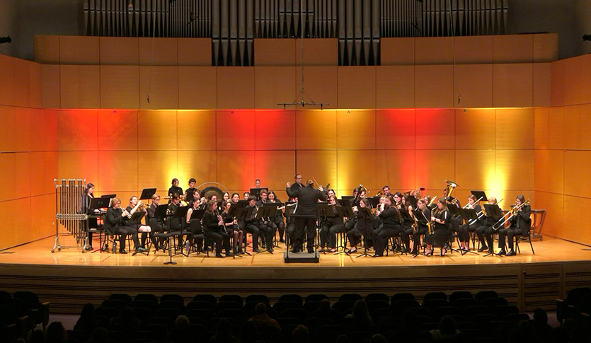 A picture of the CMU University Band performing in Staples Family Concert Hall under the direction of Eric Strasshofer.
