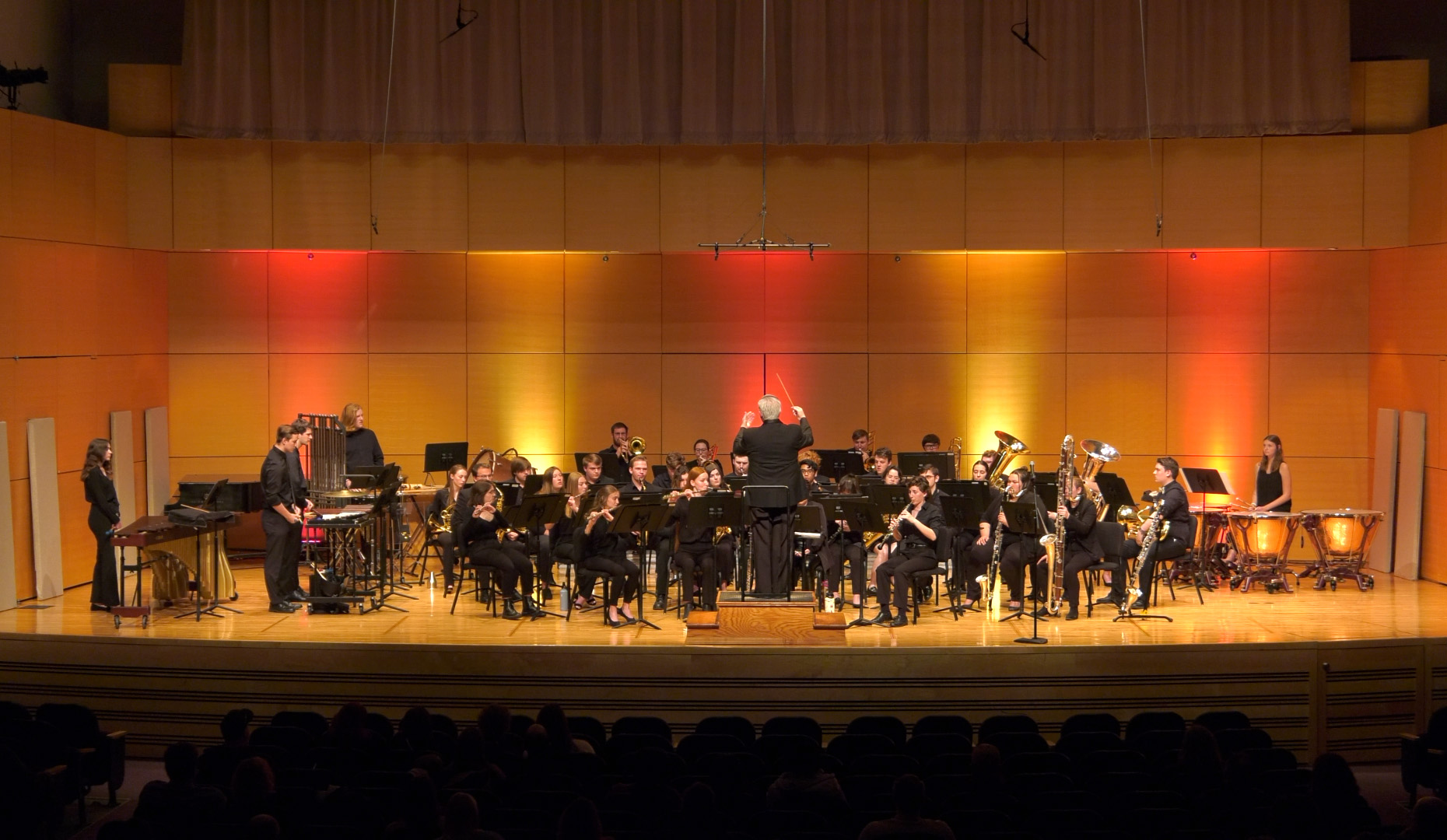 The CMU Wind Symphony, under the direction of Dr. James Batchelor, is performing on stage at Staples Family Concert Hall.