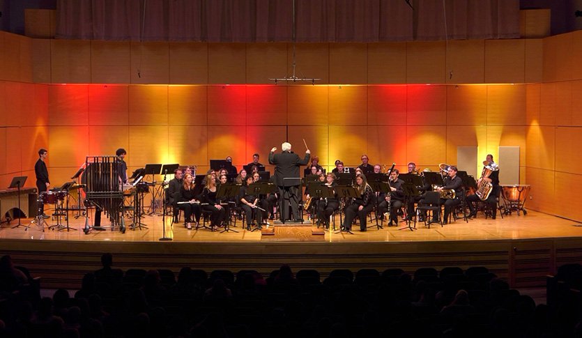 A picture of the CMU Wind Symphony performing on stage in Staples Family Concert Hall under the direction of Dr. Batcheller.