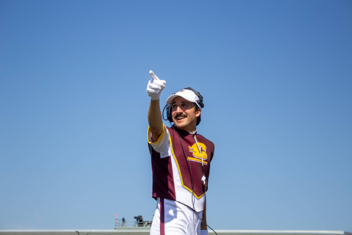 a man wearing a Chippewa Marching Band uniform pointing and smiling