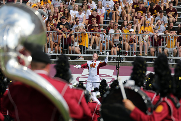 The Central Michigan University Drum Major conducts the marching band at a football game.