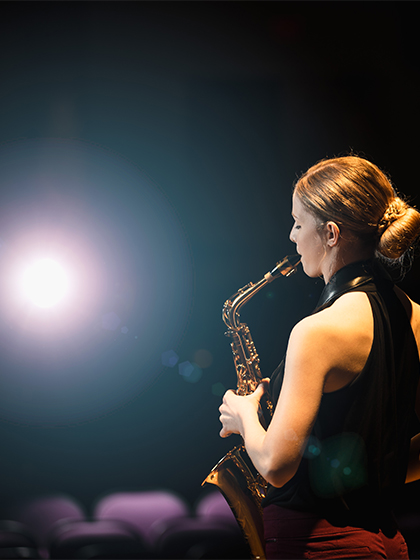 A student from the School of Music at Central Michigan University in the spotlight playing the saxophone.