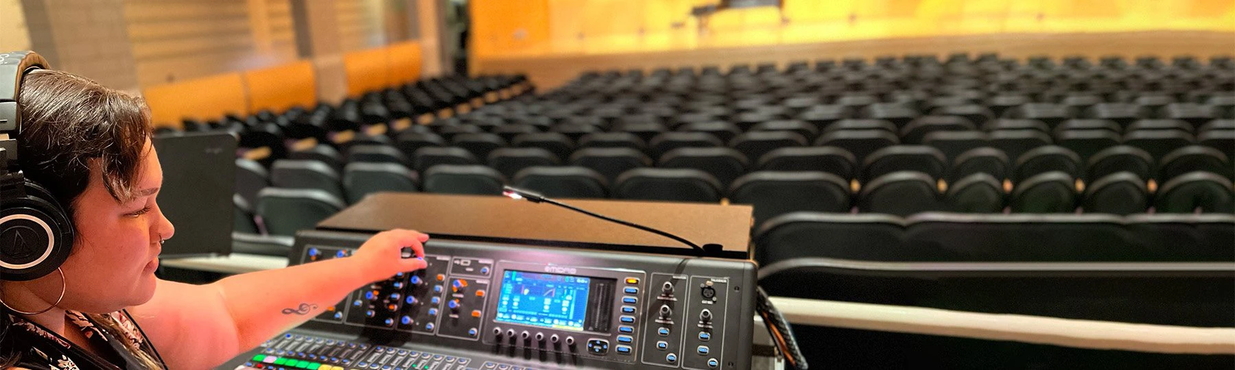 A picture of a student making adjustments at a sound console at Staples Family Concert Hall