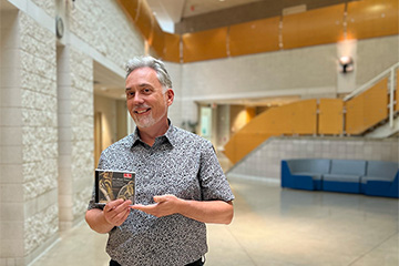 A picture of CMU Horn Faculty Bruce Bonnell holding his recently released album 
