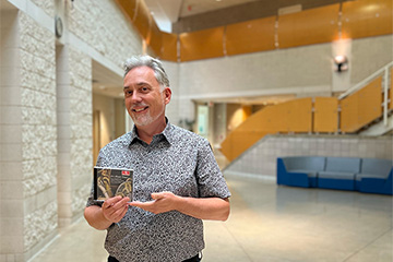 A picture of CMU Horn Faculty Bruce Bonnell holding his recently released album
