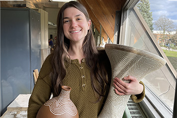 A picture of CMU student Melissa Navarre holding two ceramic percussion instruments she created
