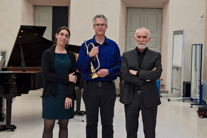 2025-08-06 Mueller 720x480 3 Individuals smiling and dressed in concert performance attire. From left to right stands Francesca Carola, pianist, Neil Mueller, trumpet, and Ivano Ascari, trumpet.