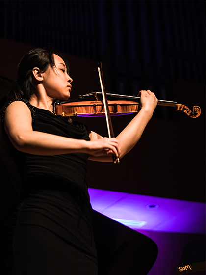 A student from the School of Music at Central Michigan University performs on a string instrument.