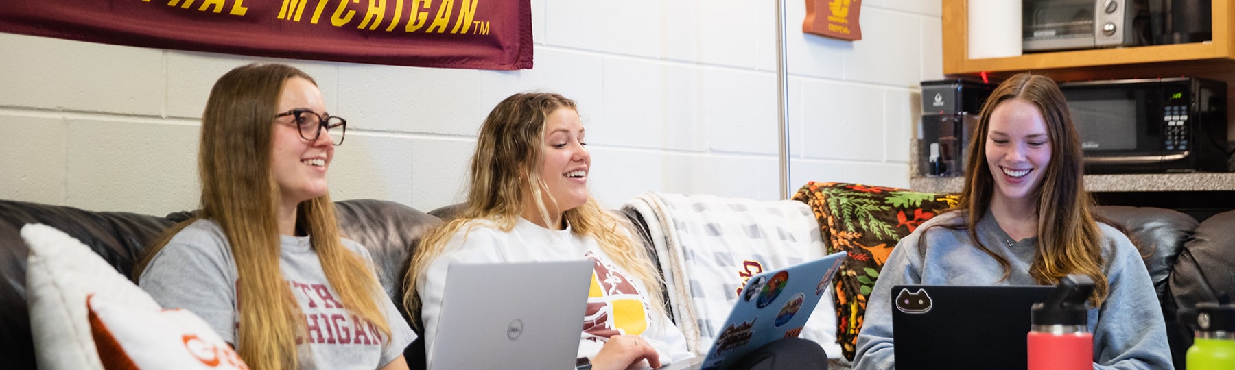 Students in dorm room with laptops working on social media