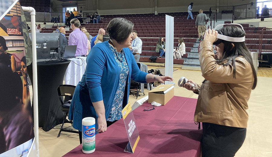 A faculty member shows a student how to use the virtual reality headset for the presentation skills center.