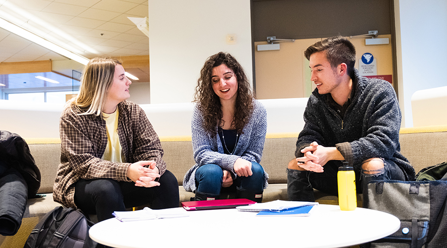 Three students from a student organization sit around a table talking.