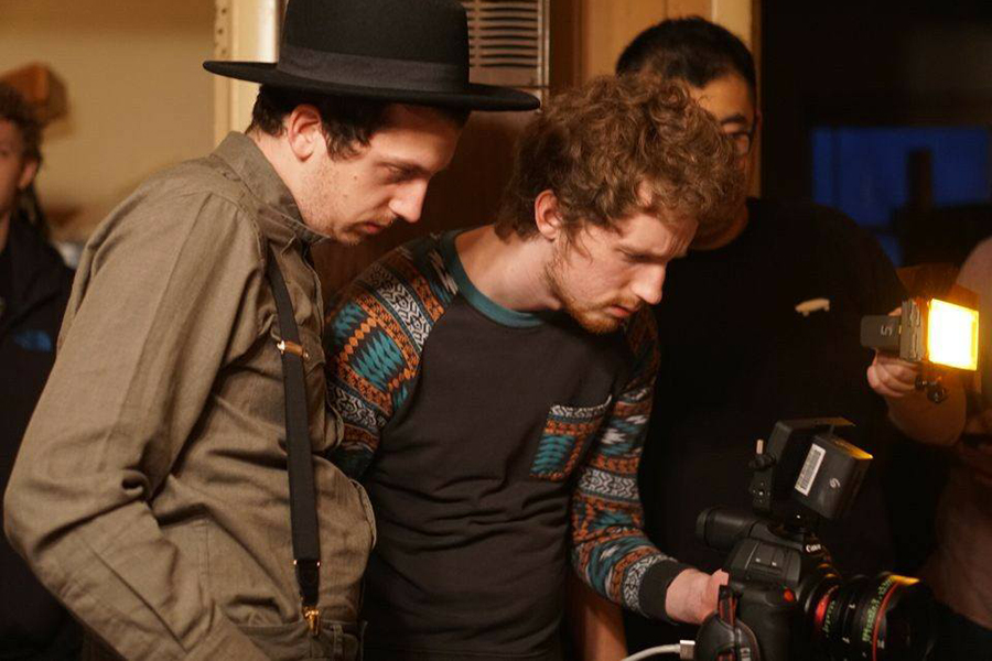 Two students watch the digital screen on their camera to see how the shot looks in the film they are making.