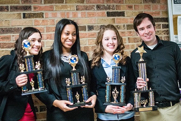 Four students pose with their trophies after winning a debate competition.