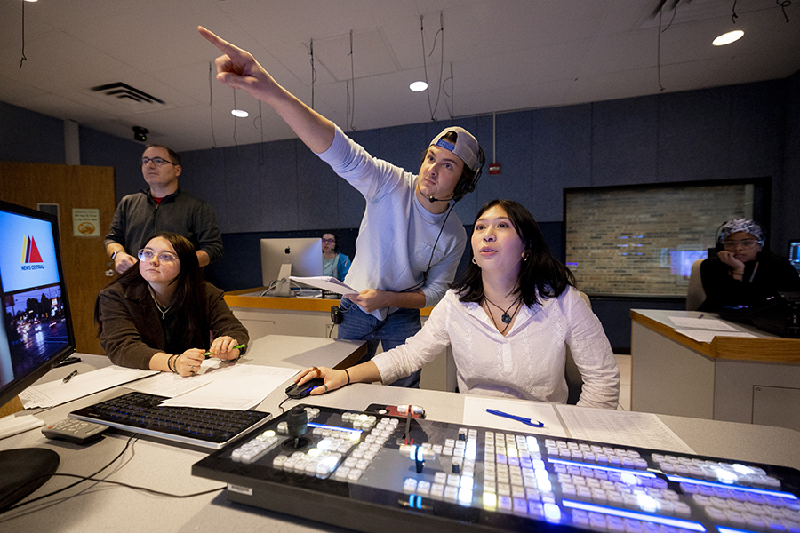 Students working each station within the sound booth during the news broadcast that airs from the campus tv station.