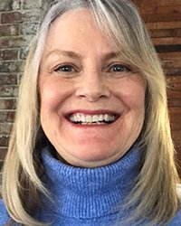 Headshot of Jeanne Ambrose in front of a brick wall.