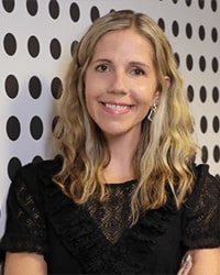 Headshot of Nikki Little. She is leaning against a white wall with black polka dots.