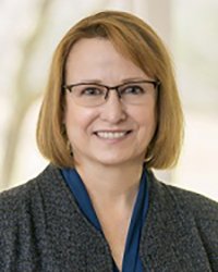 Headshot of Sarah Opperman with a white and gold backdrop.