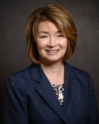 Picture of a woman in a blue suit in front of a dark background.