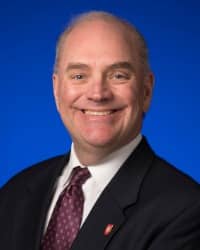 Picture of a man in a suit in front of a blue background.