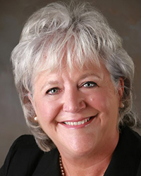 Headshot of Betsy Pollard Rau with a dark grey backdrop.