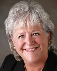 Headshot of Betsy Pollard Rau with a dark grey backdrop.