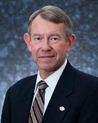 Headshot of Jim Vruggink on a black and blue backdrop.