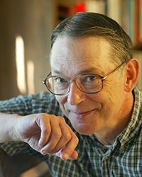 Headshot of John Palen. There's a bookshelf in the background.