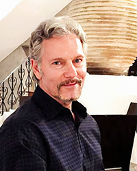 Headshot of Ken Gal with a staircase and vase behind him.