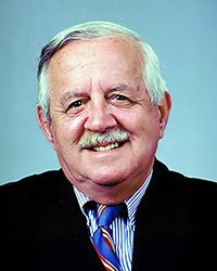 Headshot of David C Smith in a suit and tie in front of a blue backdrop.