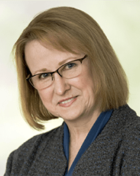 Headshot of Sarah Opperman in front of a soft green backdrop.