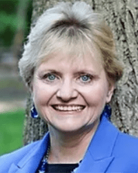 Headshot a Sheila Gruber McLean. She is leaning against a tree.