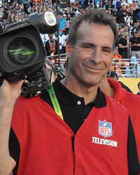 20250626_MHoF_DCornelli_001_200x250 Headshot of Don Cornelli. He's on the field, wearing his official NFL Television vest, holding a video camera.